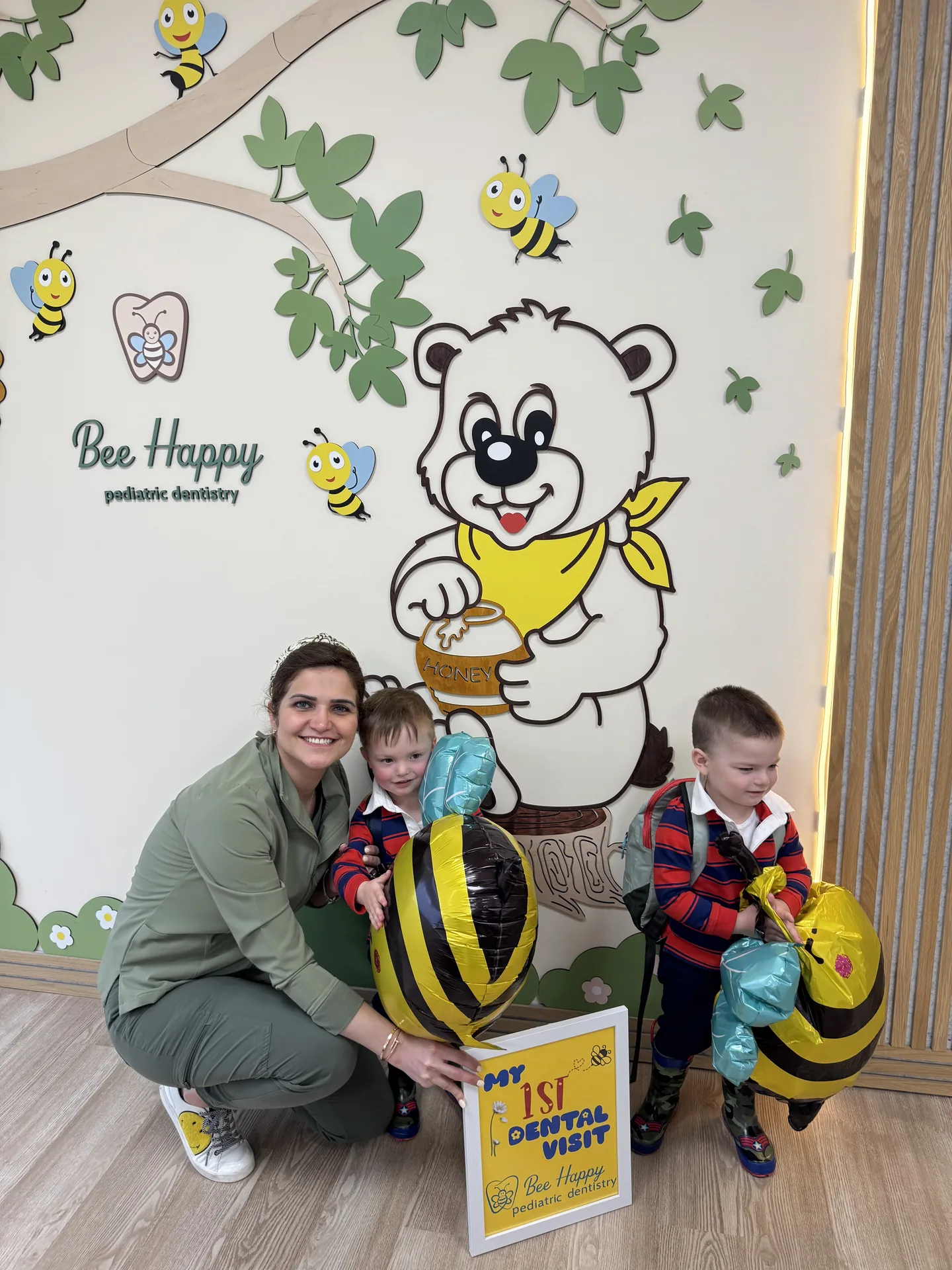 Dr. B celebrating two toddlers' first dental visit with bee balloons at Bee Happy Pediatric Dentistry